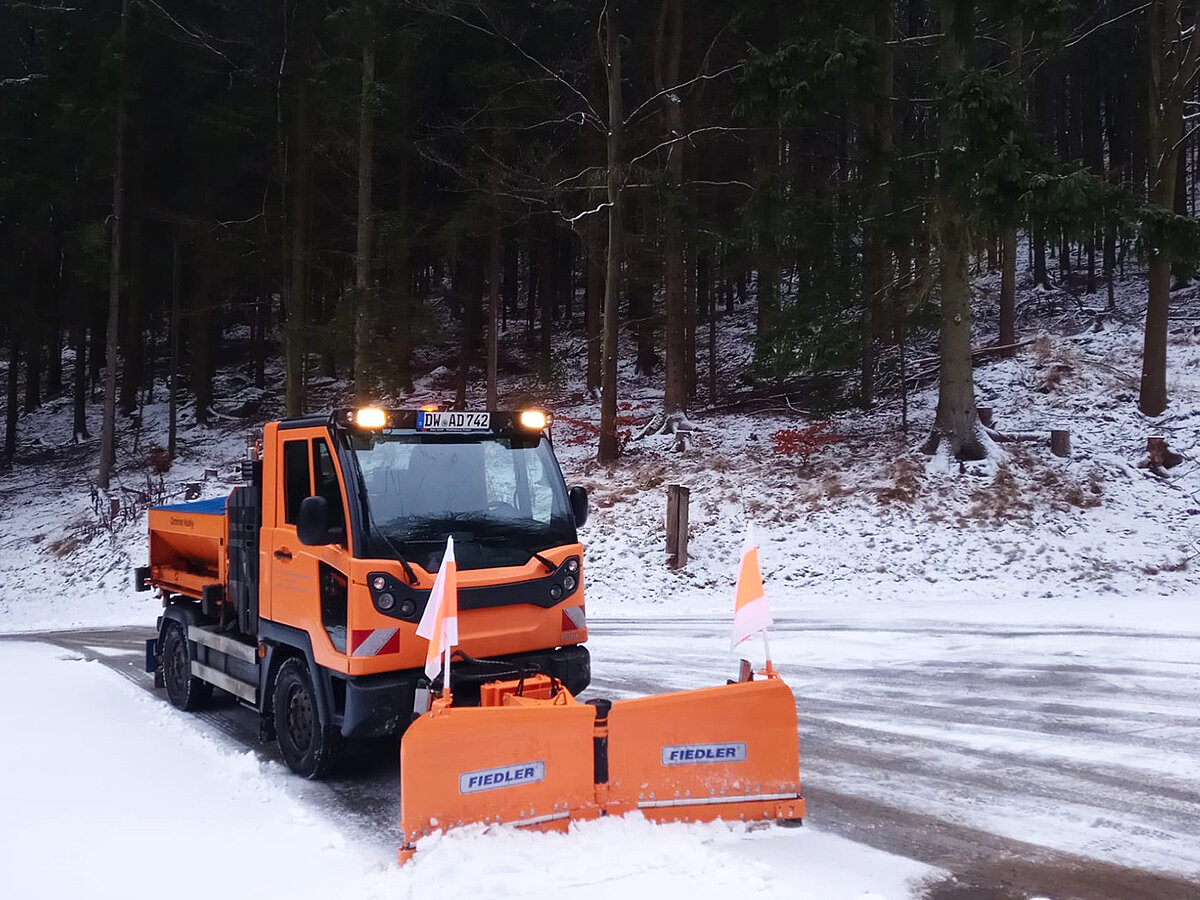 Ein Schneepflug, fährt um eine Kurve