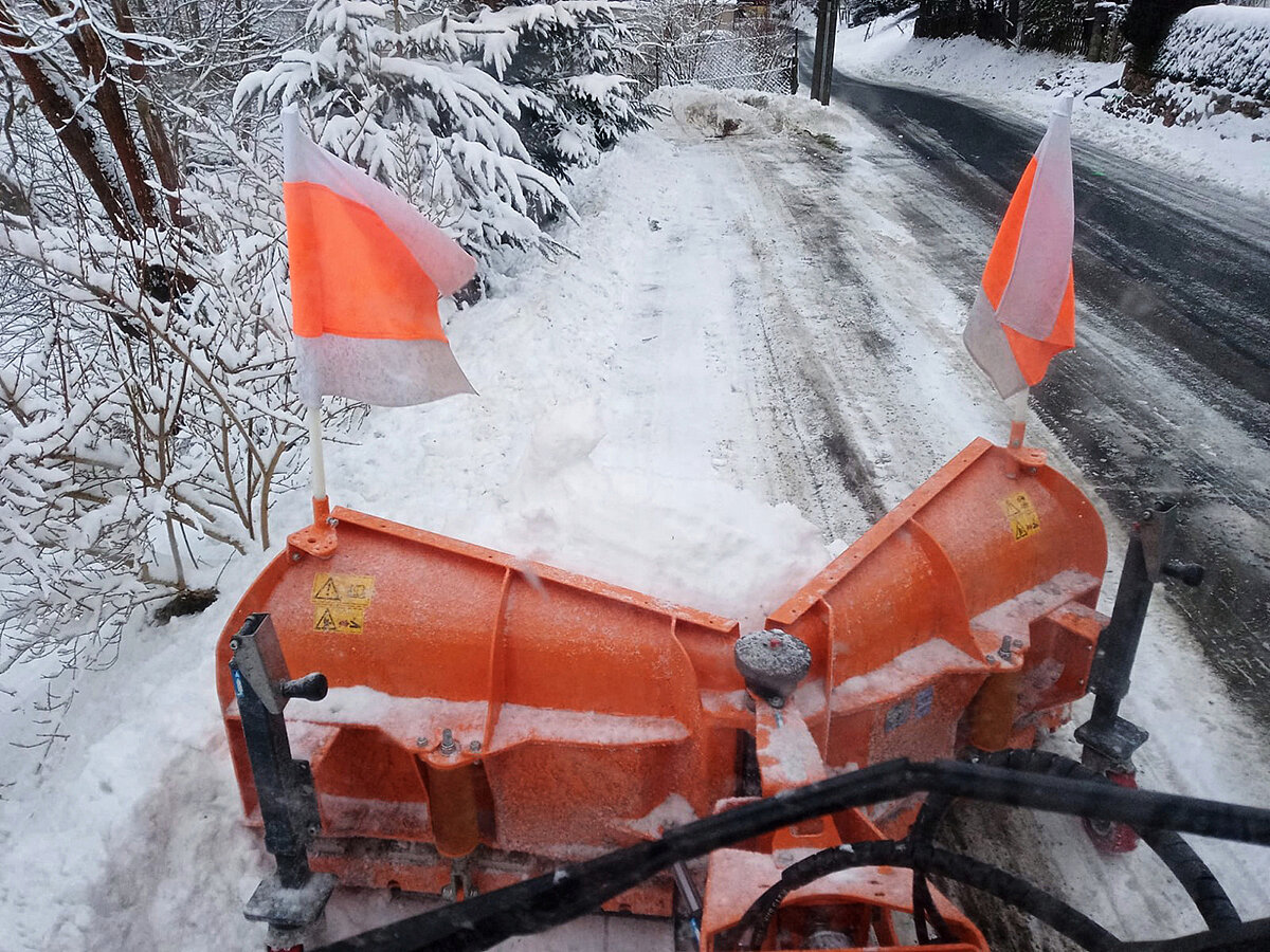 Sicht aus der Fahrerkabine eines Winterdiens-Fahrzeugs auf den Schneepflug